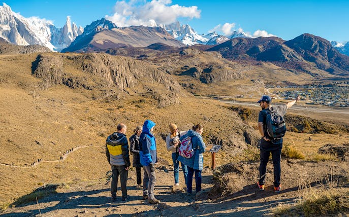 Tourists on a hiking trail in El Chaltén, Argentina, with mountains in the background.
