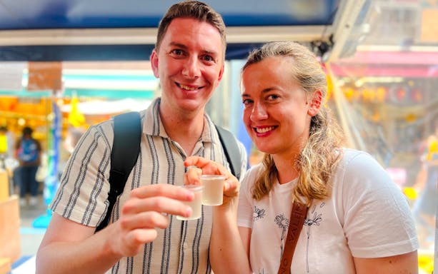Tourists tasting sake at Tsukiji Fish Market in Tokyo during a food tour.