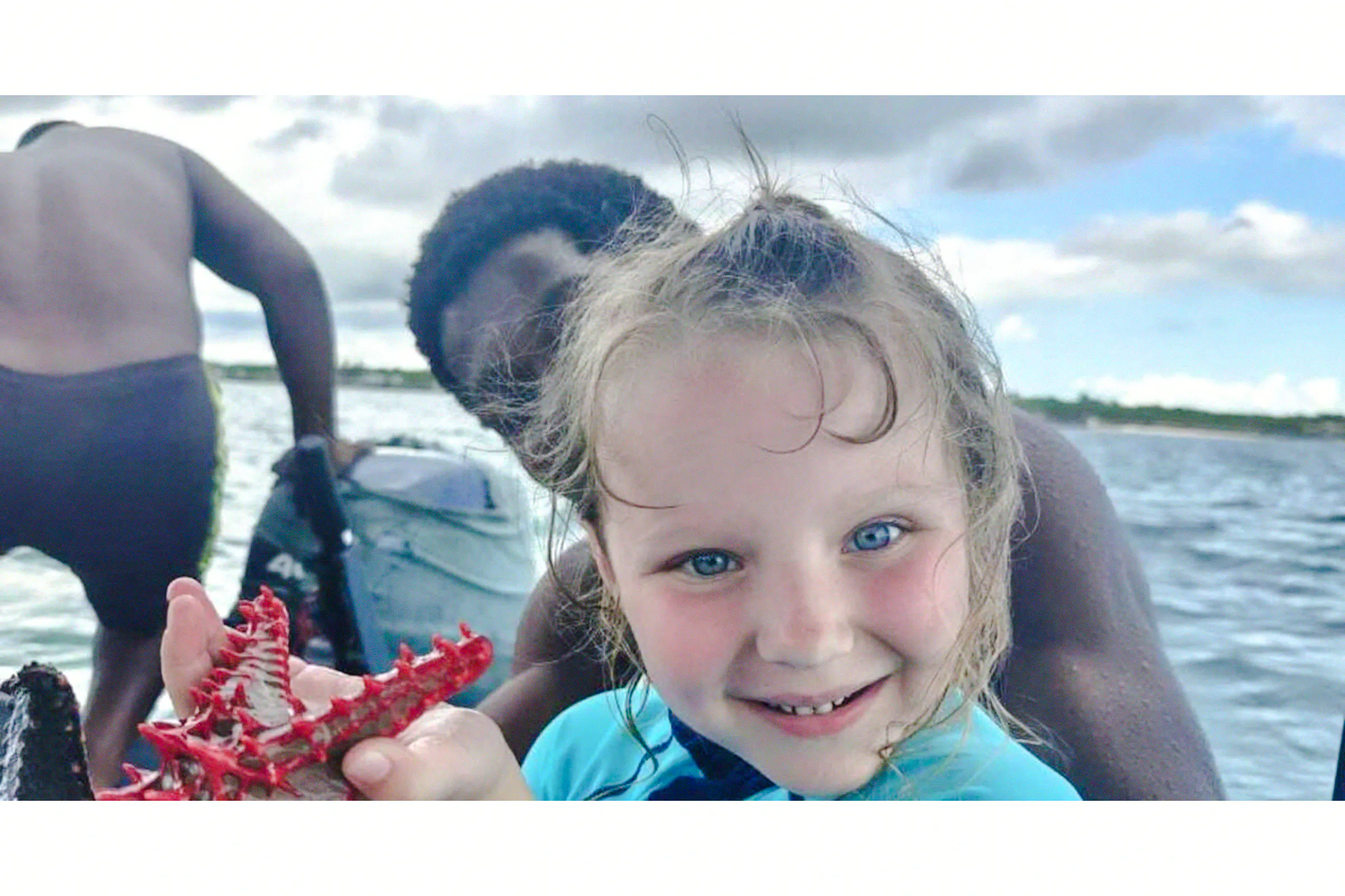 Child holding a starfish on a boat during Zanzibar day trip from Dar es Salaam.