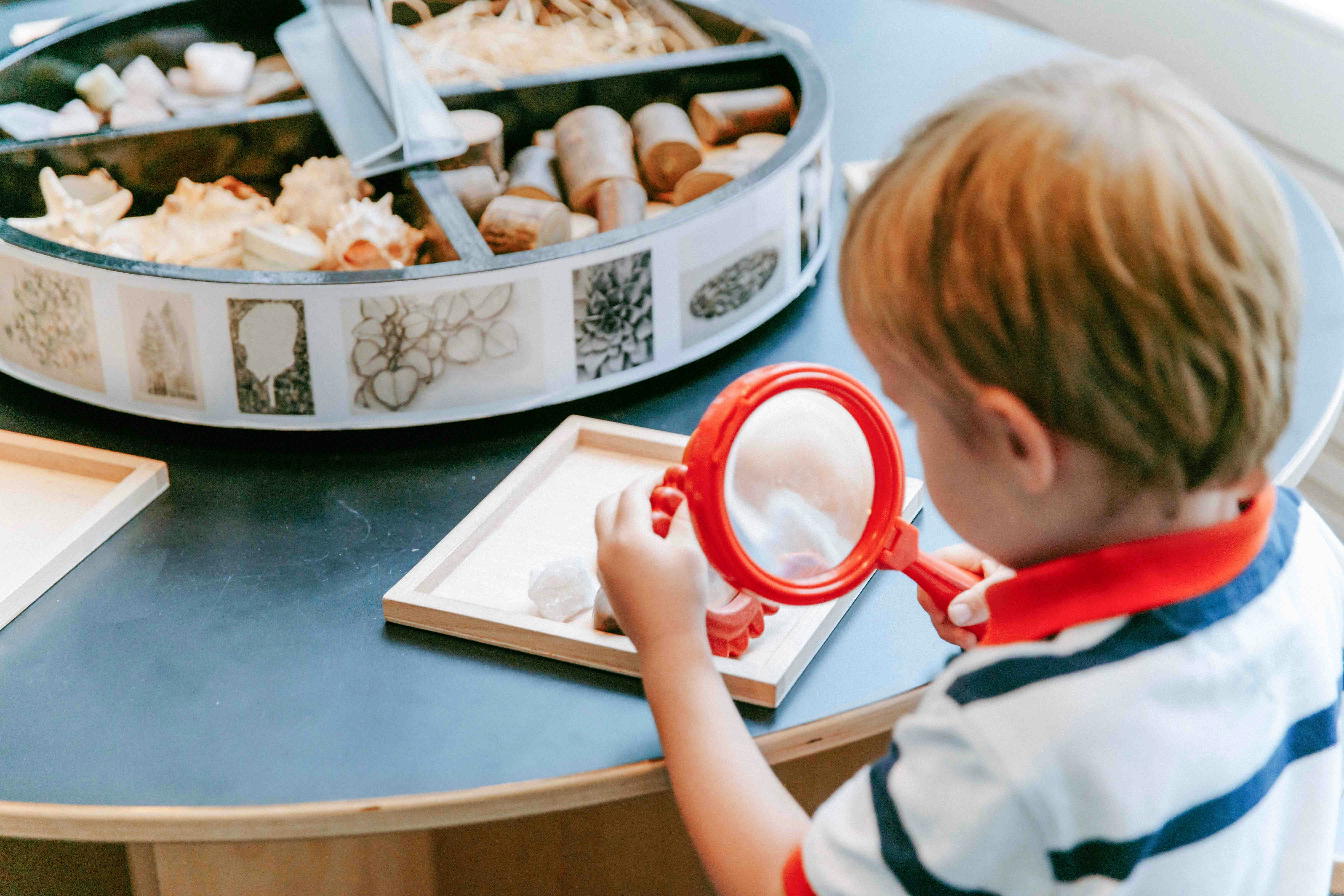 Child examining objects with magnifying glass at MoMA digital archive exhibit.