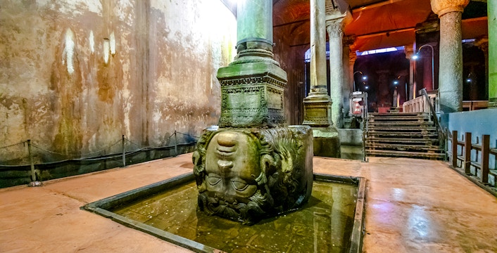Medusa head column in Basilica Cistern, Istanbul, partially submerged in water.