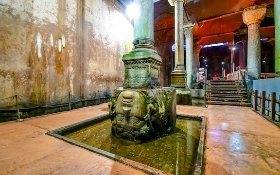 Medusa head column in Basilica Cistern, Istanbul, partially submerged in water.