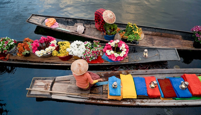 Amphawa floating market boats with vendors selling goods on a canal in Thailand.