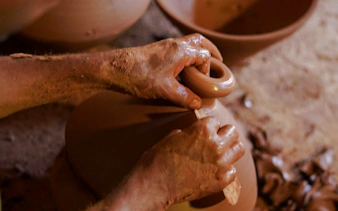 Hands shaping clay at an ancestral pottery workshop near Essaouira.