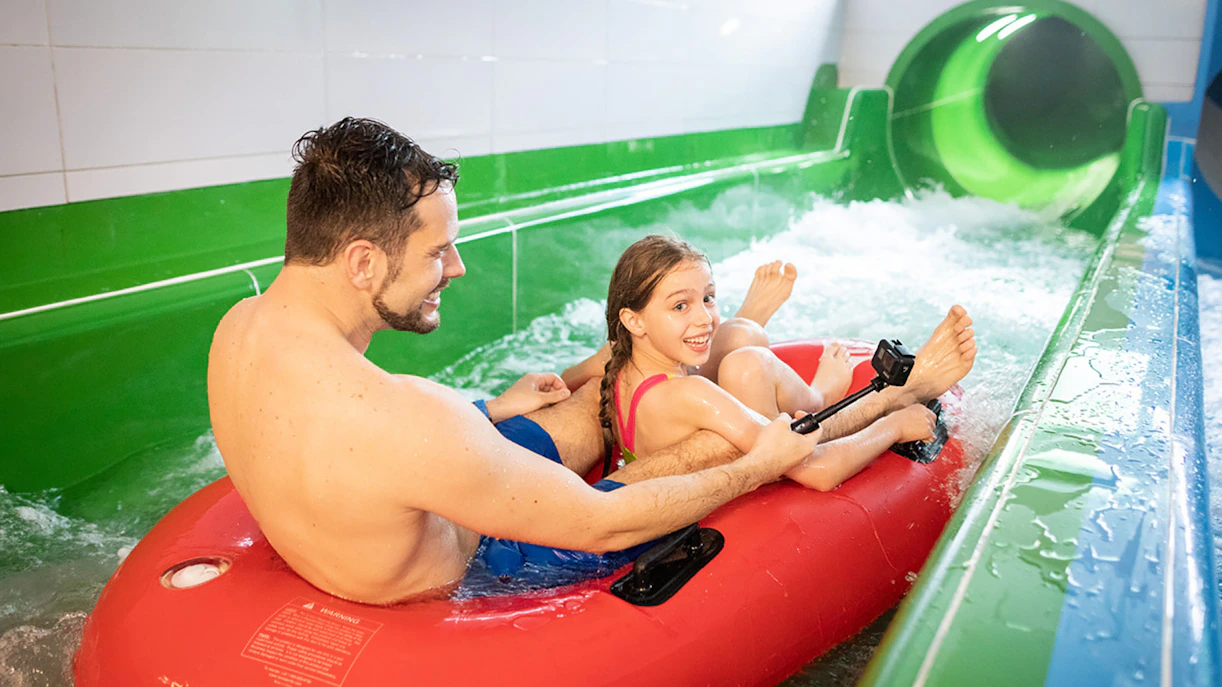 Father and daughter on a red inflatable raft at Chocholow Thermal Baths slide.