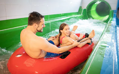 Father and daughter on a red inflatable raft at Chocholow Thermal Baths slide.