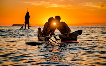 Couple paddleboarding at sunrise in Rio de Janeiro.