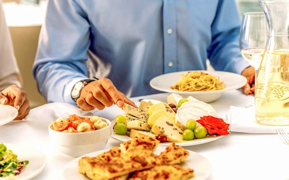 Prague dinner cruise with cheese platter, pasta, and wine on a table.