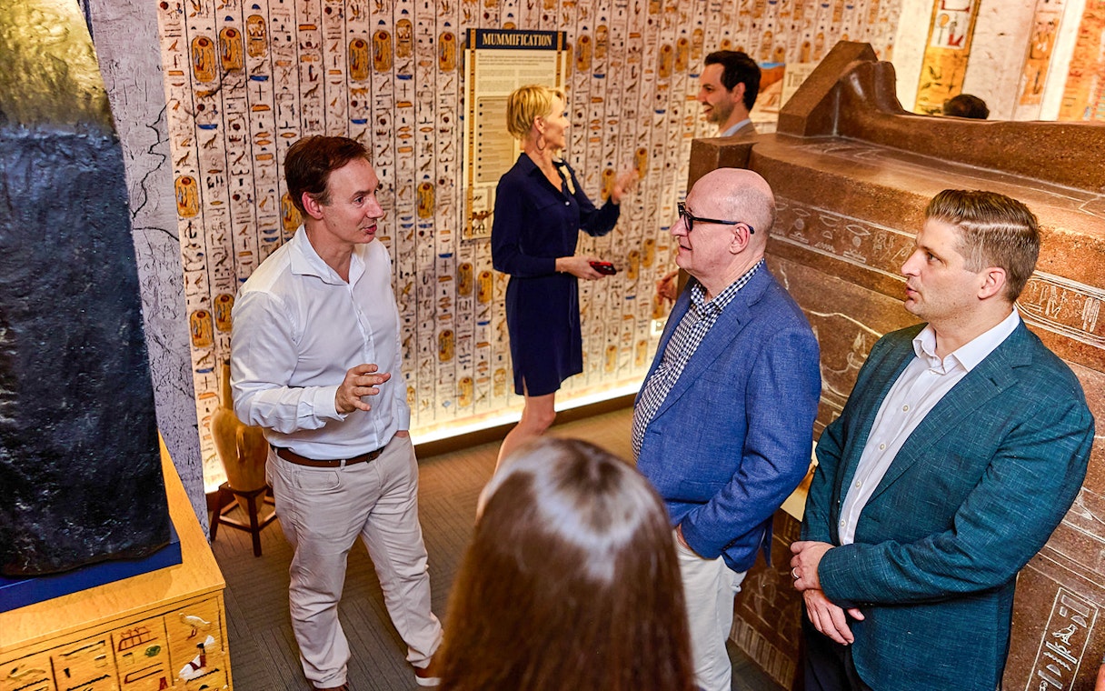 Visitors in a room with Egyptian hieroglyphs during the Tomb of the Pharaoh tour in Cairns, Australia.