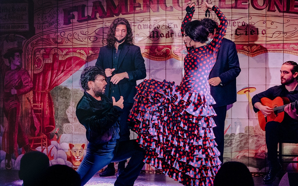 Flamenco dancers performing at Flamenco De Leones Show with guitarist in Madrid.