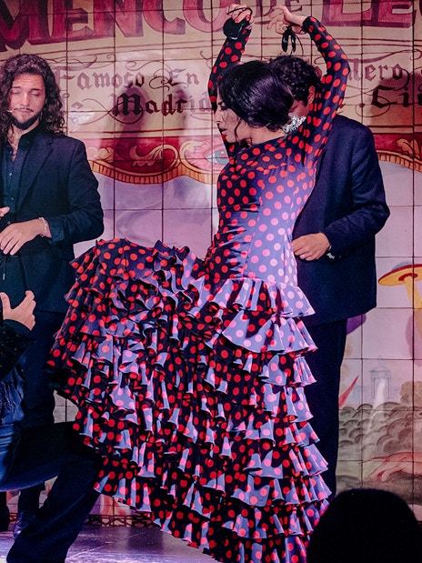 Flamenco dancers performing at Flamenco De Leones Show with guitarist in Madrid.