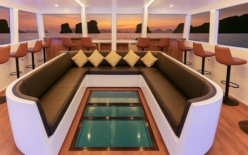 Interior seating area of Langkawi sunset cruise with ocean view through large windows.