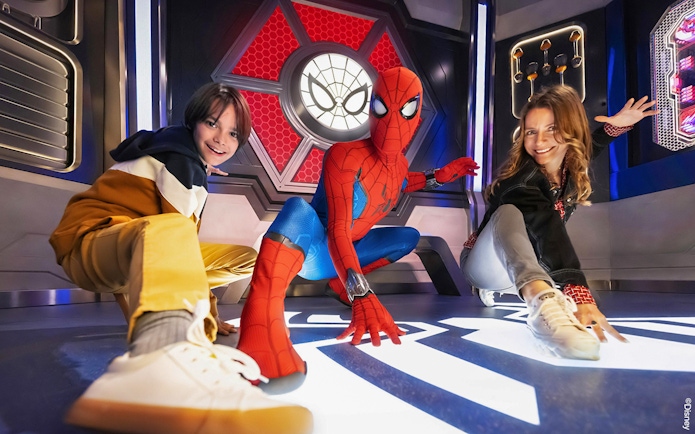 Spider-Man posing with visitors at Disneyland Paris attraction.