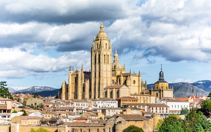 Segovia Cathedral with surrounding cityscape and mountains in the background.