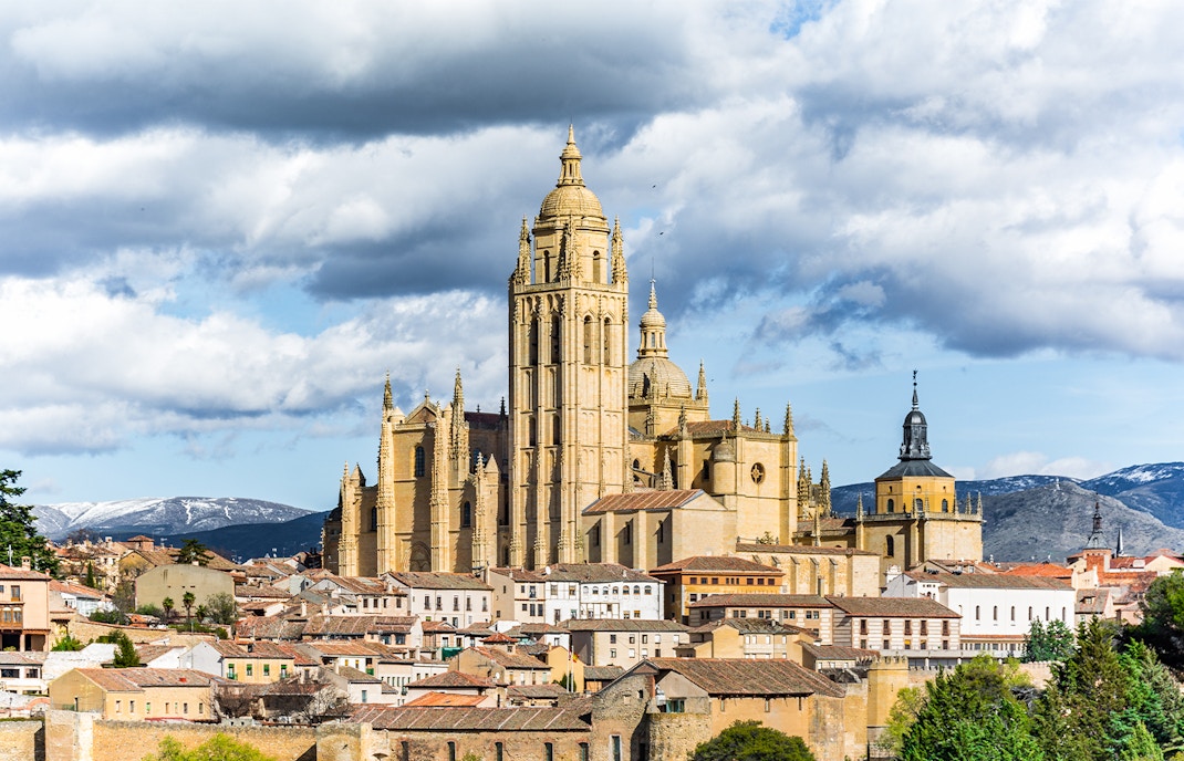 Segovia Cathedral with surrounding cityscape and mountains in the background.