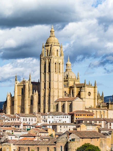 Segovia Cathedral with surrounding cityscape and mountains in the background.