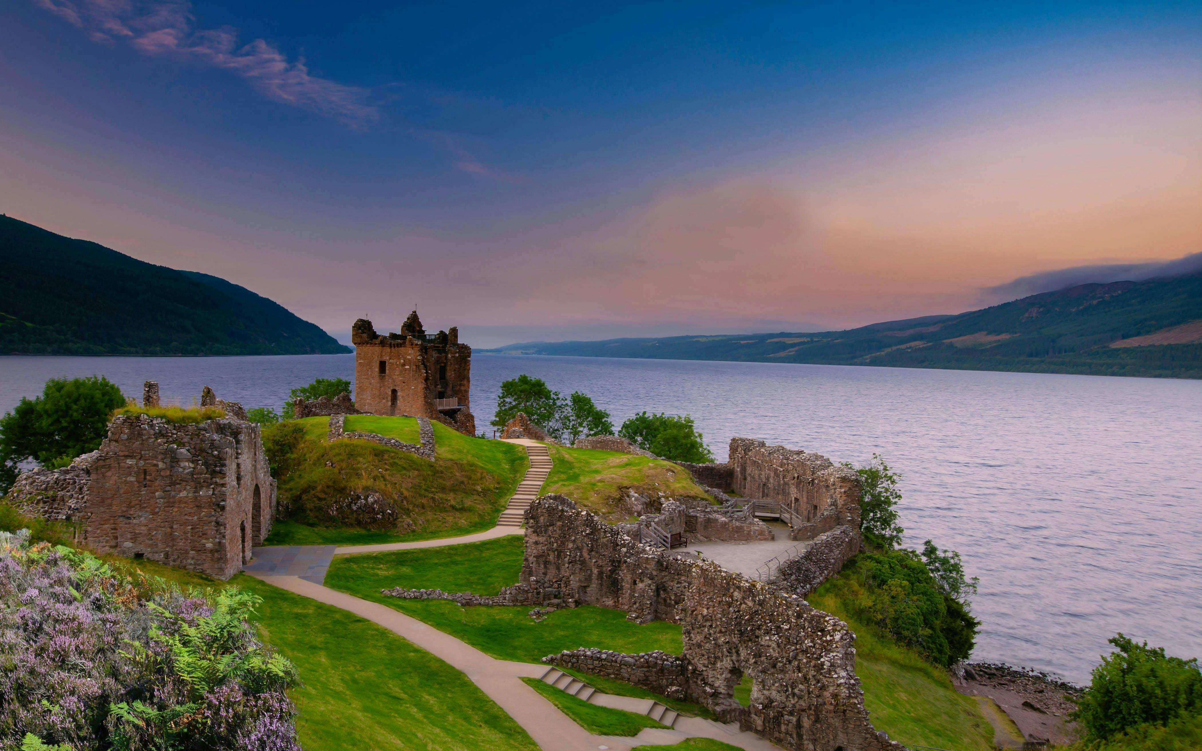 Urquhart Castle ruins overlooking Loch Ness at sunset, Scotland.