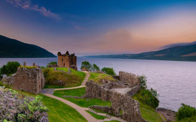 Urquhart Castle ruins overlooking Loch Ness at sunset, Scotland.