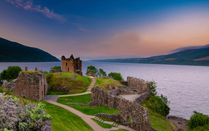 Urquhart Castle ruins overlooking Loch Ness at sunset, Scotland.