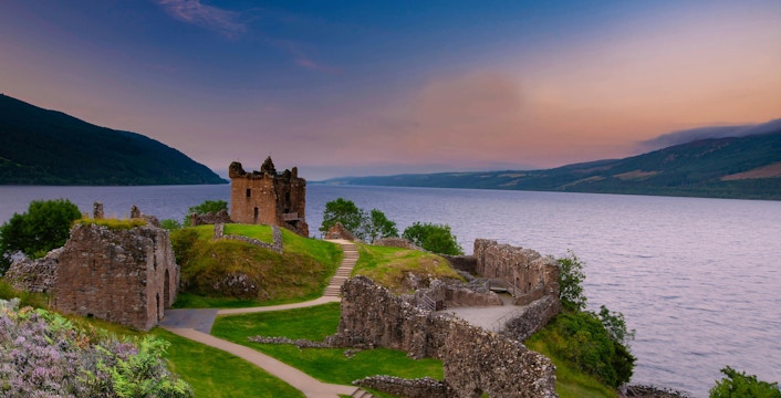 Urquhart Castle ruins overlooking Loch Ness at sunset, Scotland.