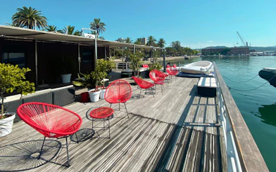 Dockside seating area with red chairs and plants in La Spezia, starting point for Cinque Terre boat tour.