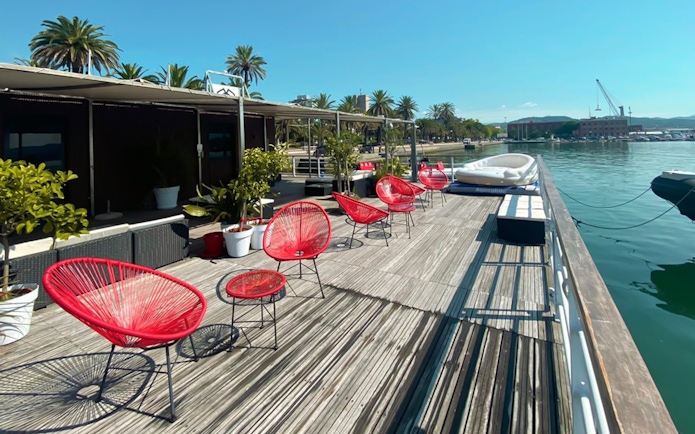 Dockside seating area with red chairs and plants in La Spezia, starting point for Cinque Terre boat tour.