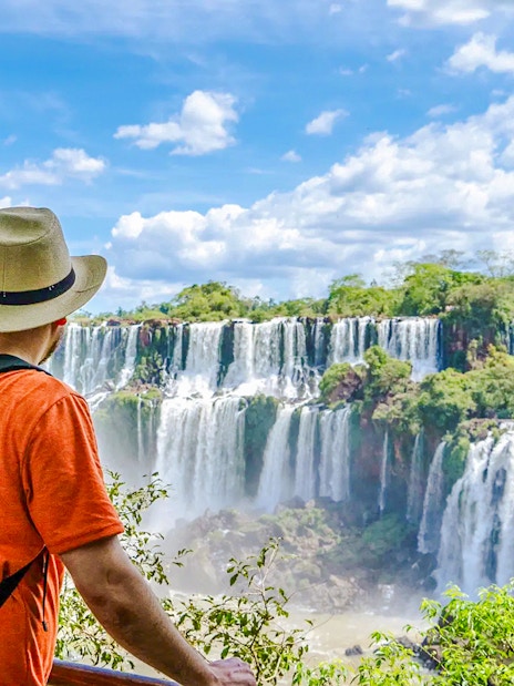 Traveler viewing Iguazu Falls in Argentina with lush greenery and cascading water.