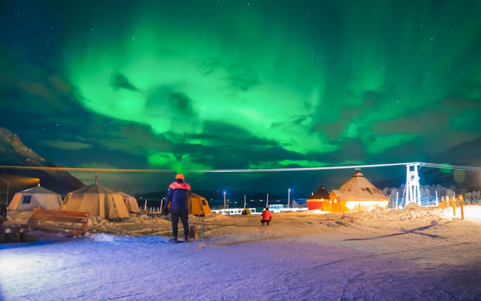Northern lights over snowy campsite in Tromso Lapland.