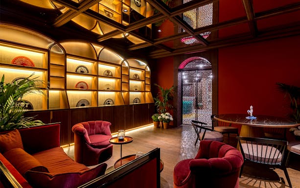 Luxurious lounge with red seating and decorative fans, part of Flamenco de Leones Show experience.