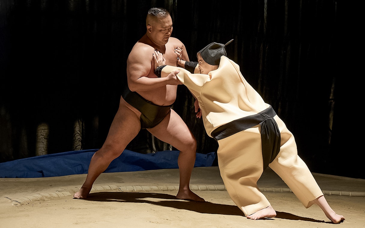 Sumo wrestler and opponent in traditional attire at Sumo Hall Hirakuza, Osaka.