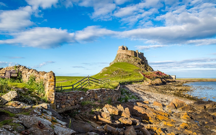 Lindisfarne Castle on rocky hill with stone wall, Northumberland coast, England.