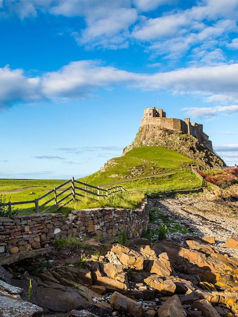 Lindisfarne Castle on rocky hill with stone wall, Northumberland coast, England.