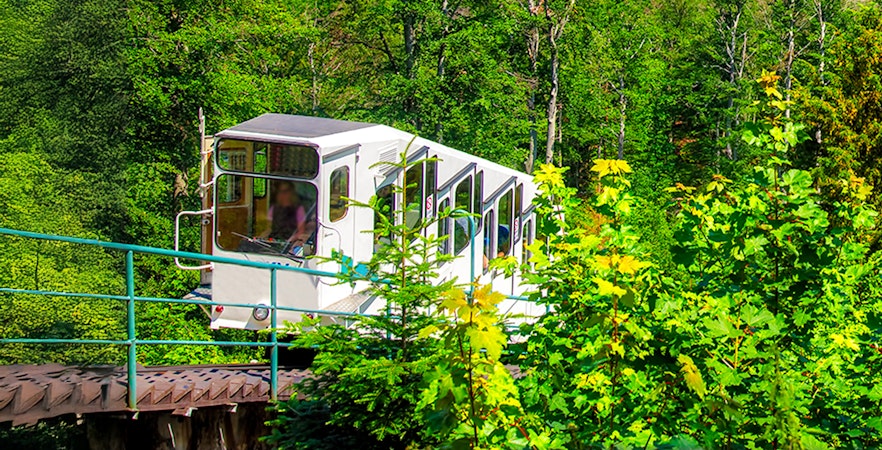 Funicular ascending through lush forest in Karlovy Vary.