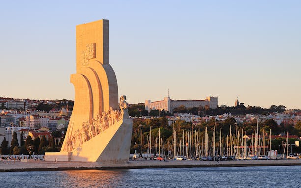 Padrão dos Descobrimentos monument in Lisbon at sunset with cityscape in background.