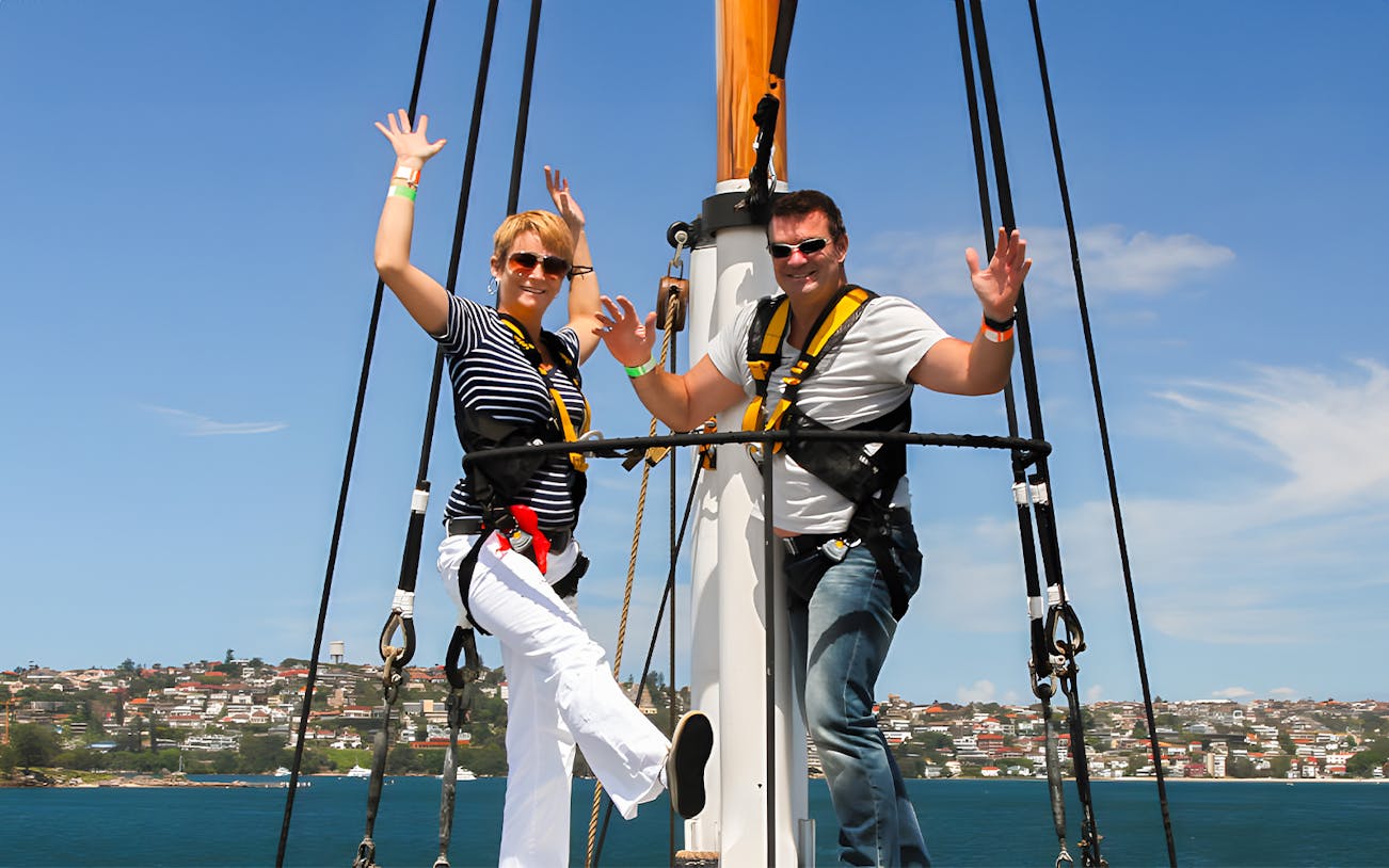 Couple enjoying a tall ship cruise on Sydney Harbour with cityscape in background.