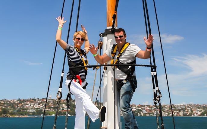 Couple enjoying a tall ship cruise on Sydney Harbour with cityscape in background.