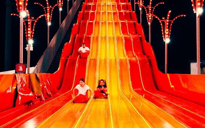 Children sliding down a colorful slide at Lusail Winter Wonderland.