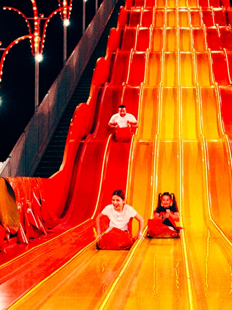 Children sliding down a colorful slide at Lusail Winter Wonderland.