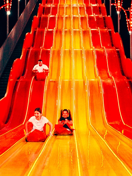 Children sliding down a colorful slide at Lusail Winter Wonderland.