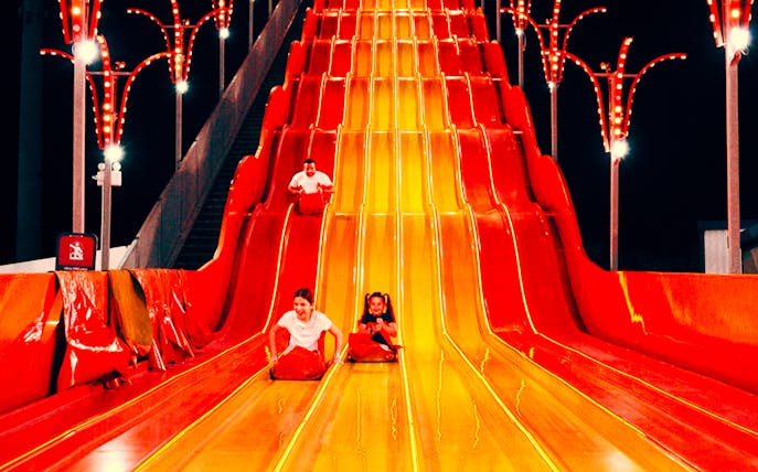 Children sliding down a colorful slide at Lusail Winter Wonderland.