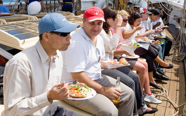 People enjoying a meal on a tall ship cruise on Sydney Harbour.