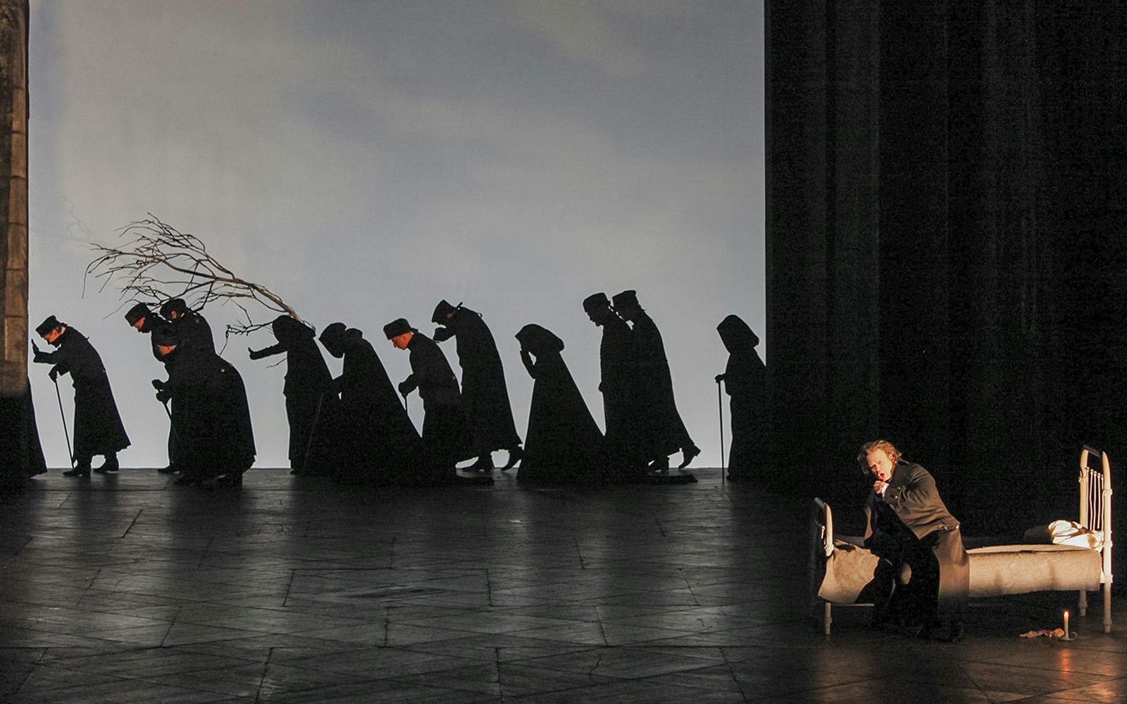 Performers in dark costumes on stage during "The Queen of Spades" opera scene.