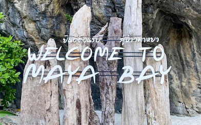 Welcome sign at Maya Bay Island with wooden posts and rocky background.