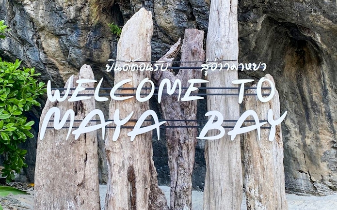 Welcome sign at Maya Bay Island with wooden posts and rocky background.