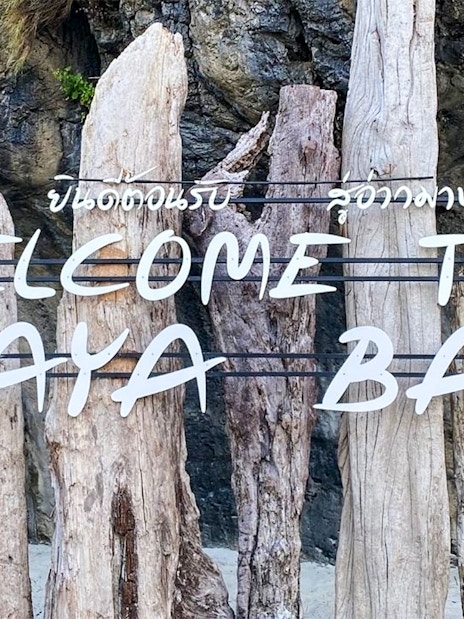 Welcome sign at Maya Bay Island with wooden posts and rocky background.