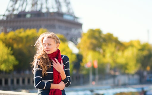 Person standing near Eiffel Tower with Parisian bridge in background.