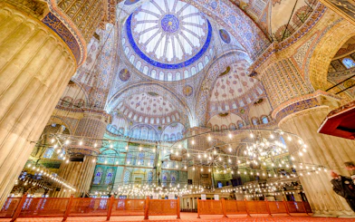 Interior view of the Blue Mosque in Istanbul, showcasing ornate domes and intricate tilework.
