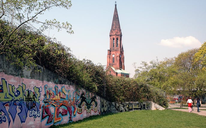Graffiti-covered wall with church tower in Kreuzberg, Berlin.