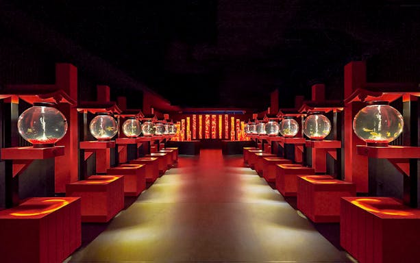 Path through Art Aquarium Museum with red stands holding lit goldfish bowls.