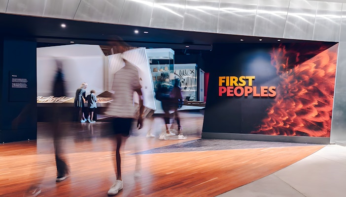 Bunjilaka First Peoples exhibit entrance at Melbourne Museum with visitors walking by.